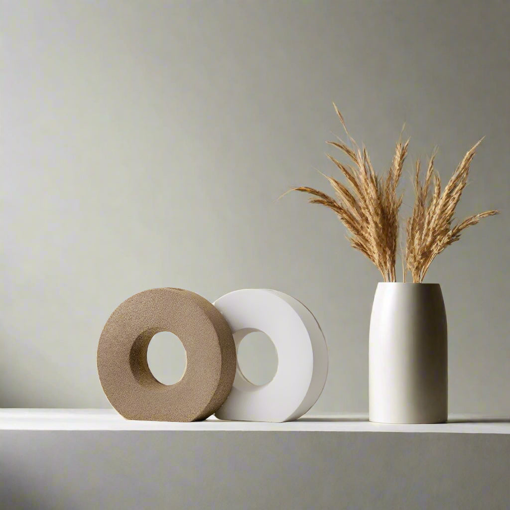 Decorative items including a round beige vase and white vase with dried grass